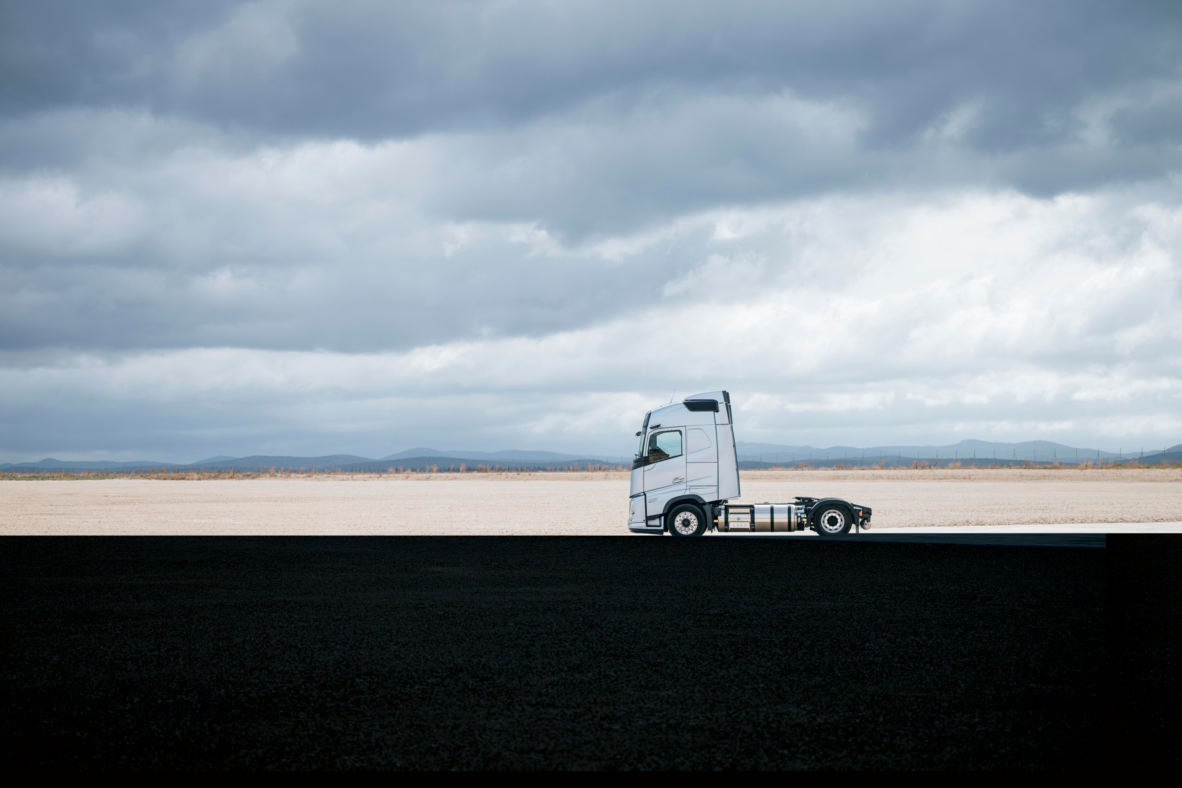 Seitenansicht eines Volvo-Lkw, der in einer weiten, offenen Landschaft unter bewölktem Himmel geparkt ist, mit ausgedehnter Umgebung und minimaler Kulisse.